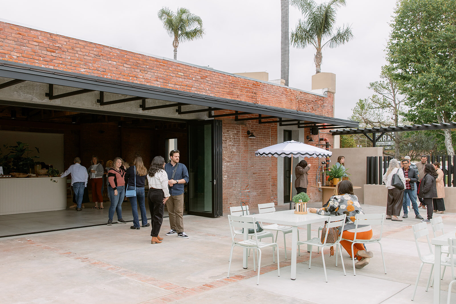 Guests gathering across Palomino’s patio and interior with the large sliding doors fully open.