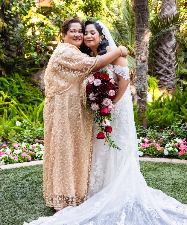 Bride embracing her mother in a garden on her wedding day