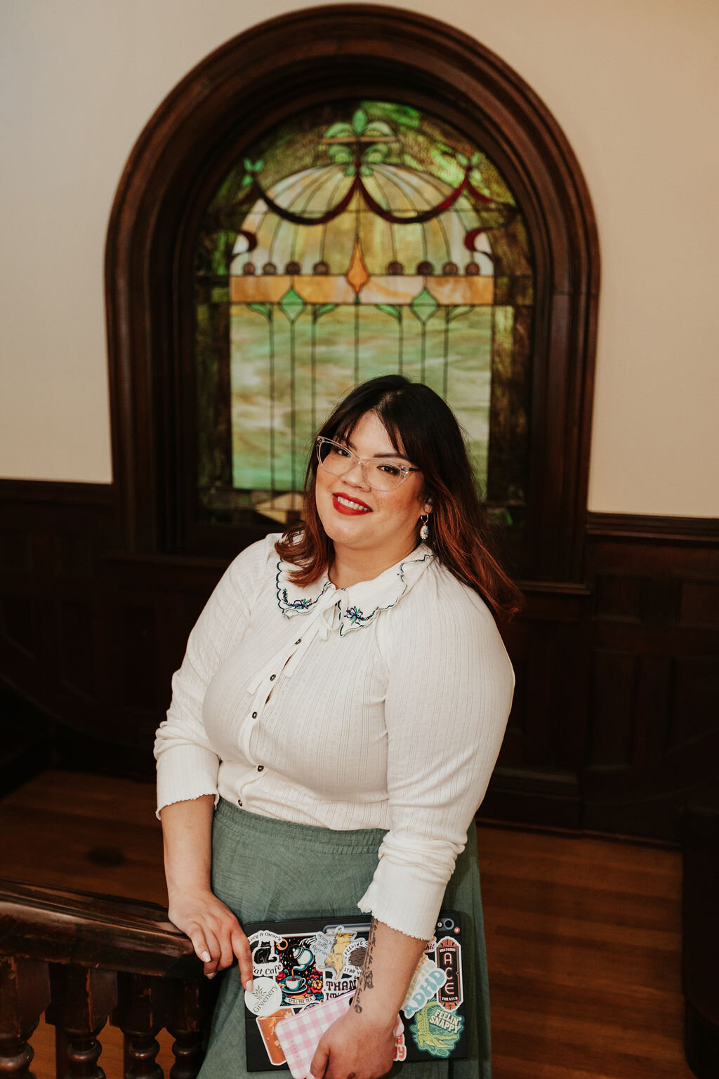 Krystal of Howie Mae, a Kentucky wedding planner, standing in a vintage home with stained glass on the staircase.