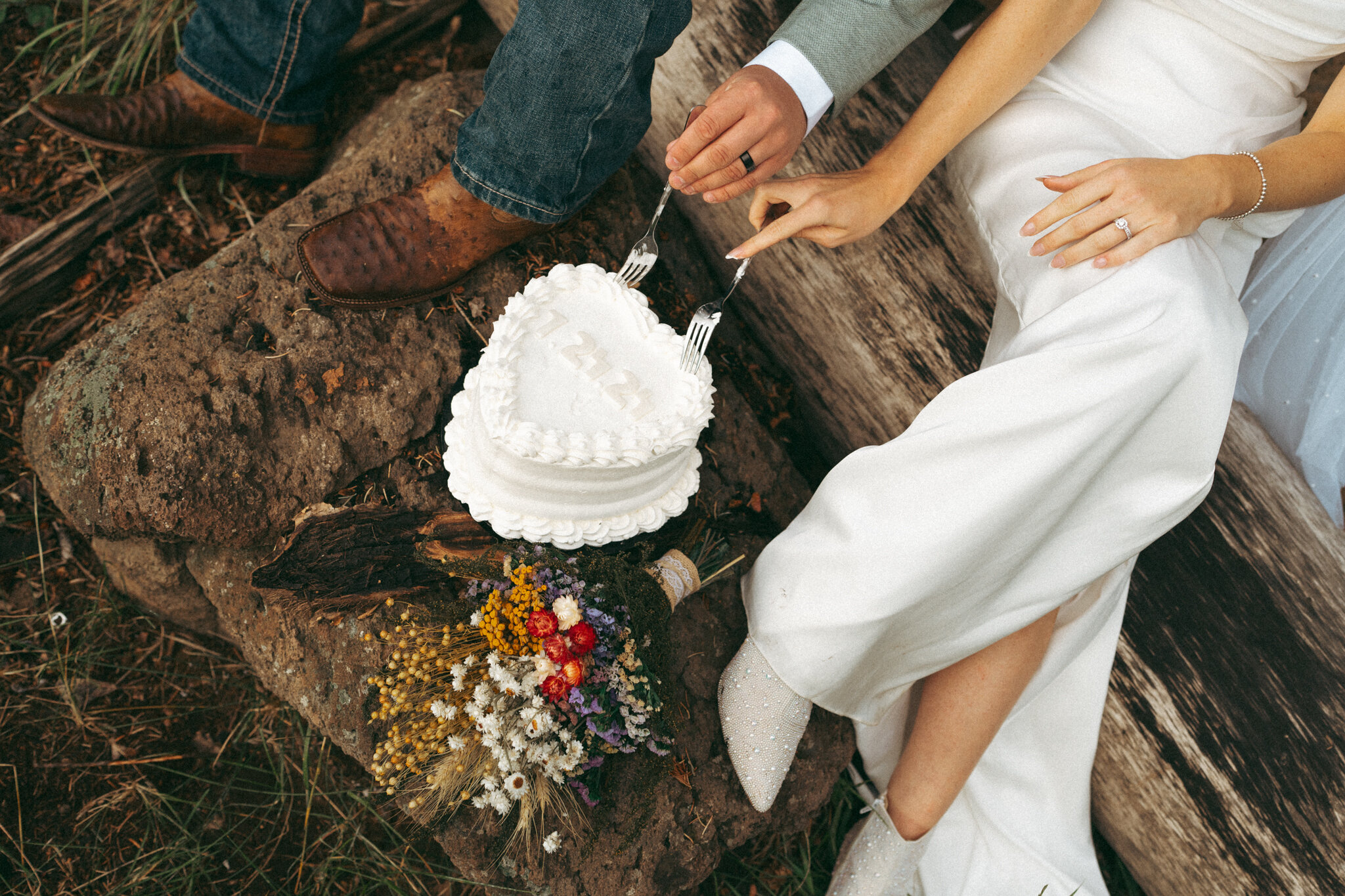 Elopement flat lay with wedding cake, and wildflowers on a pine forest floor in Flagstaff