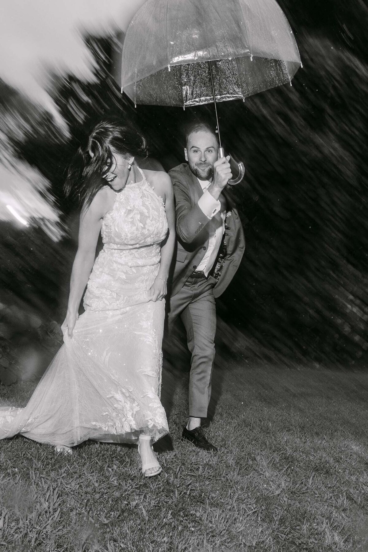 Couple laughing under a clear umbrella at night, black-and-white editorial couples photo