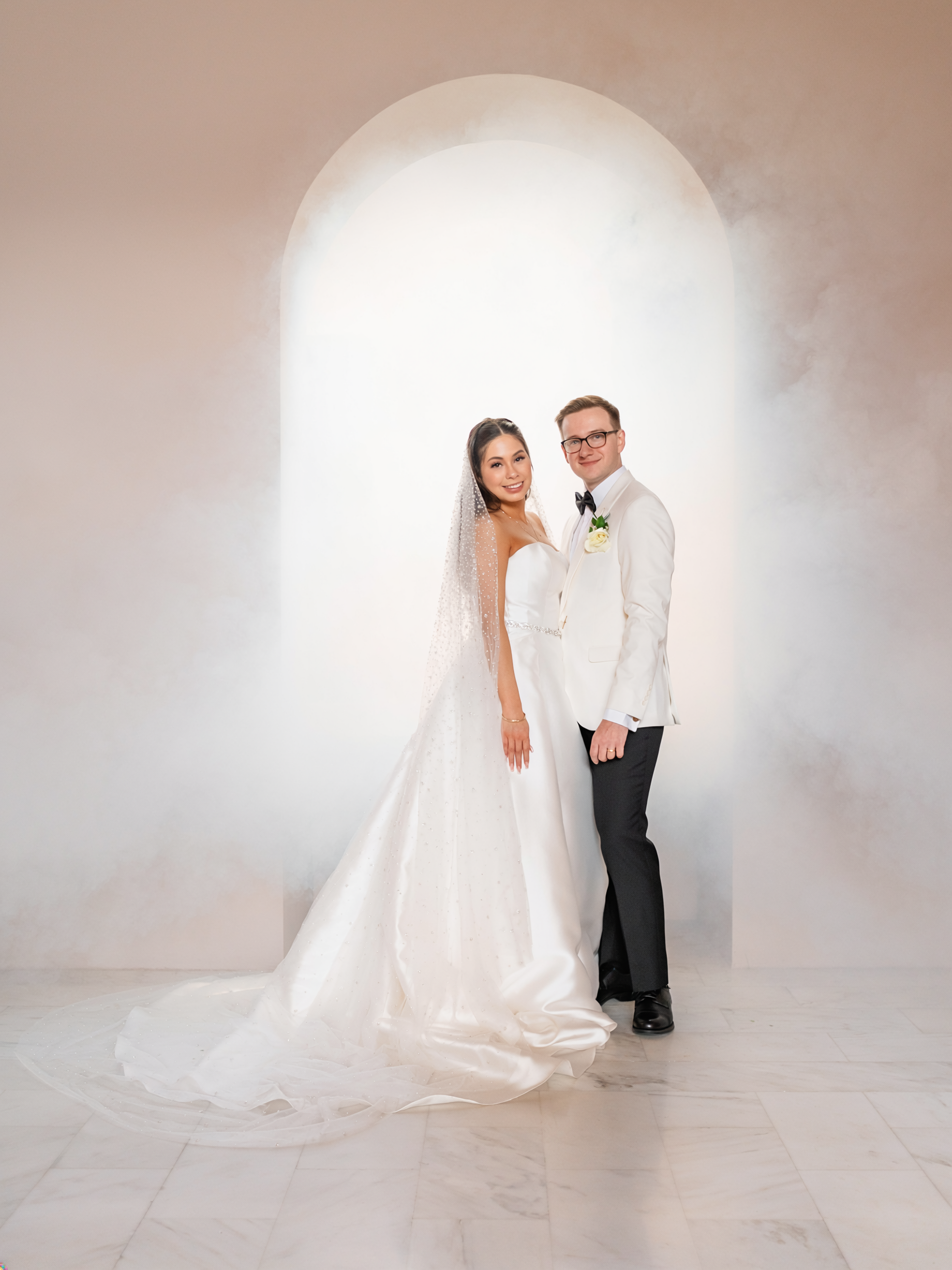 Bride and groom posed in front of a luminous minimalist arch with soft atmospheric haze