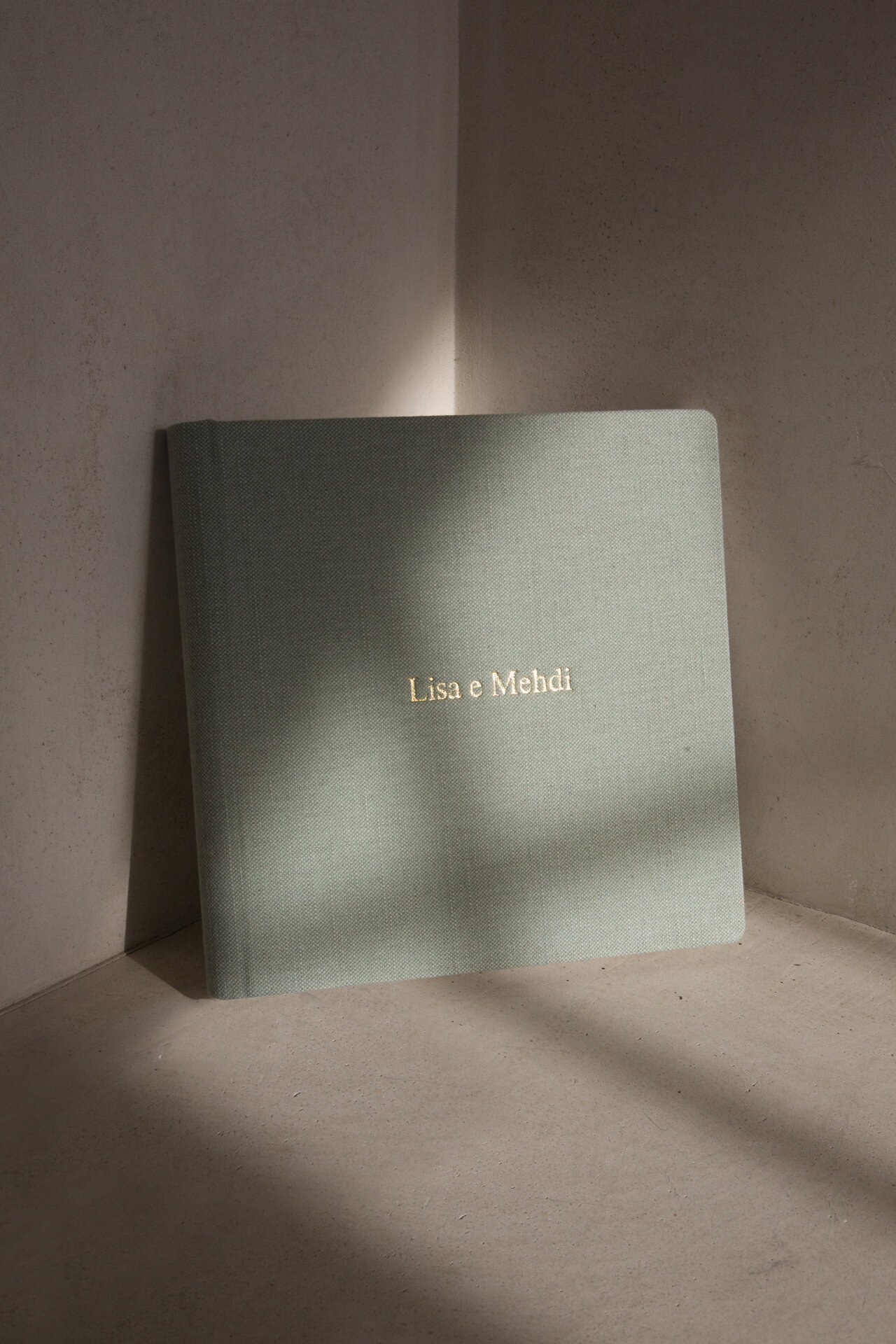 Personalized green heirloom wedding album displayed in soft light