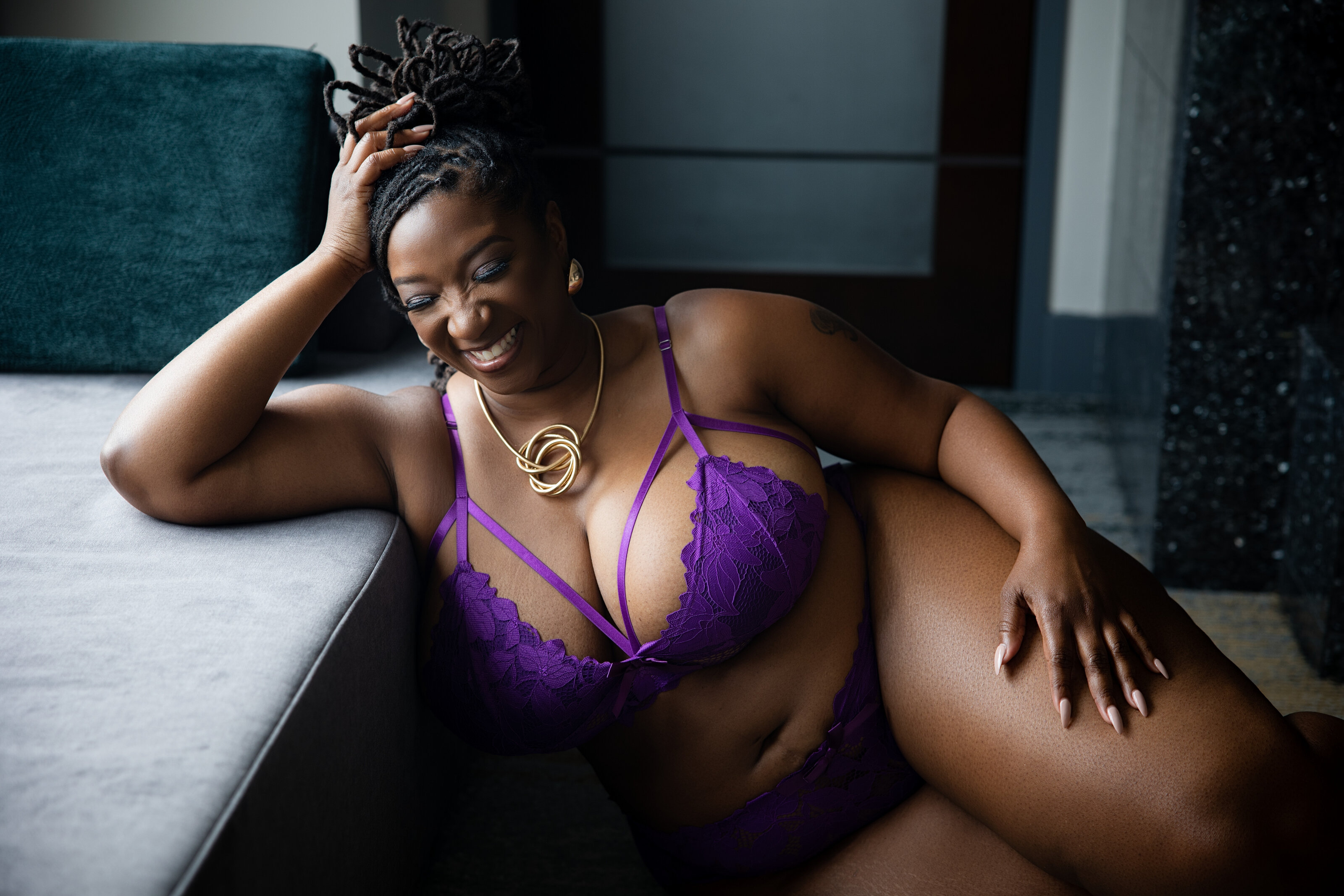 Plus size woman smiling wearing purple lingerie during a DC area boudoir session