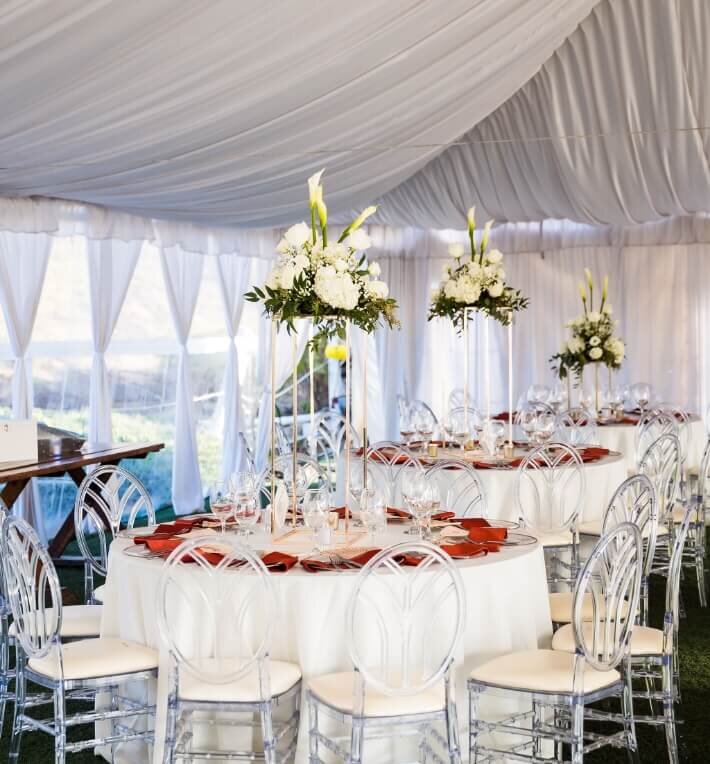 Elegant tented wedding reception with white florals and clear chairs