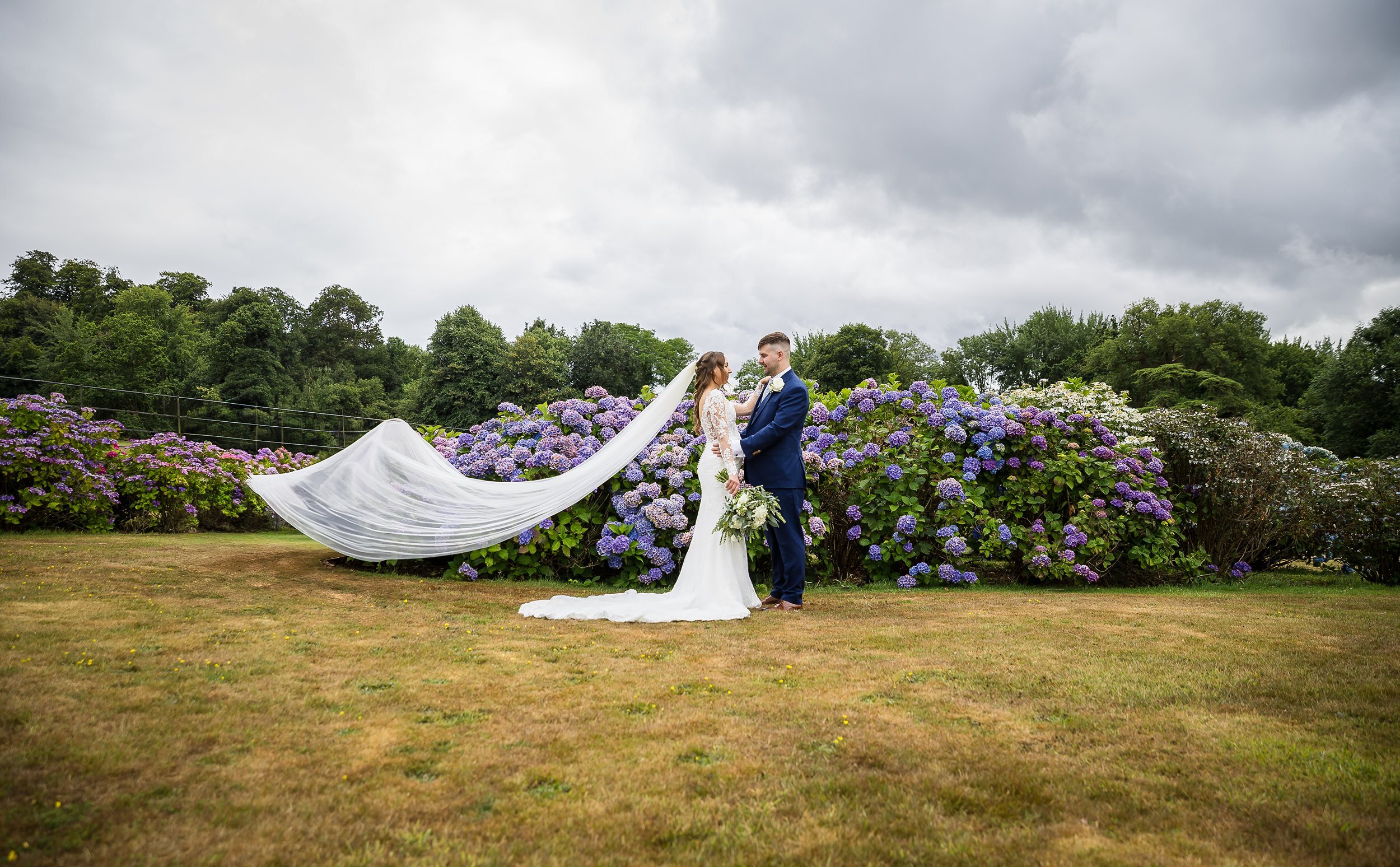 Bride and groom with flowing veil in field