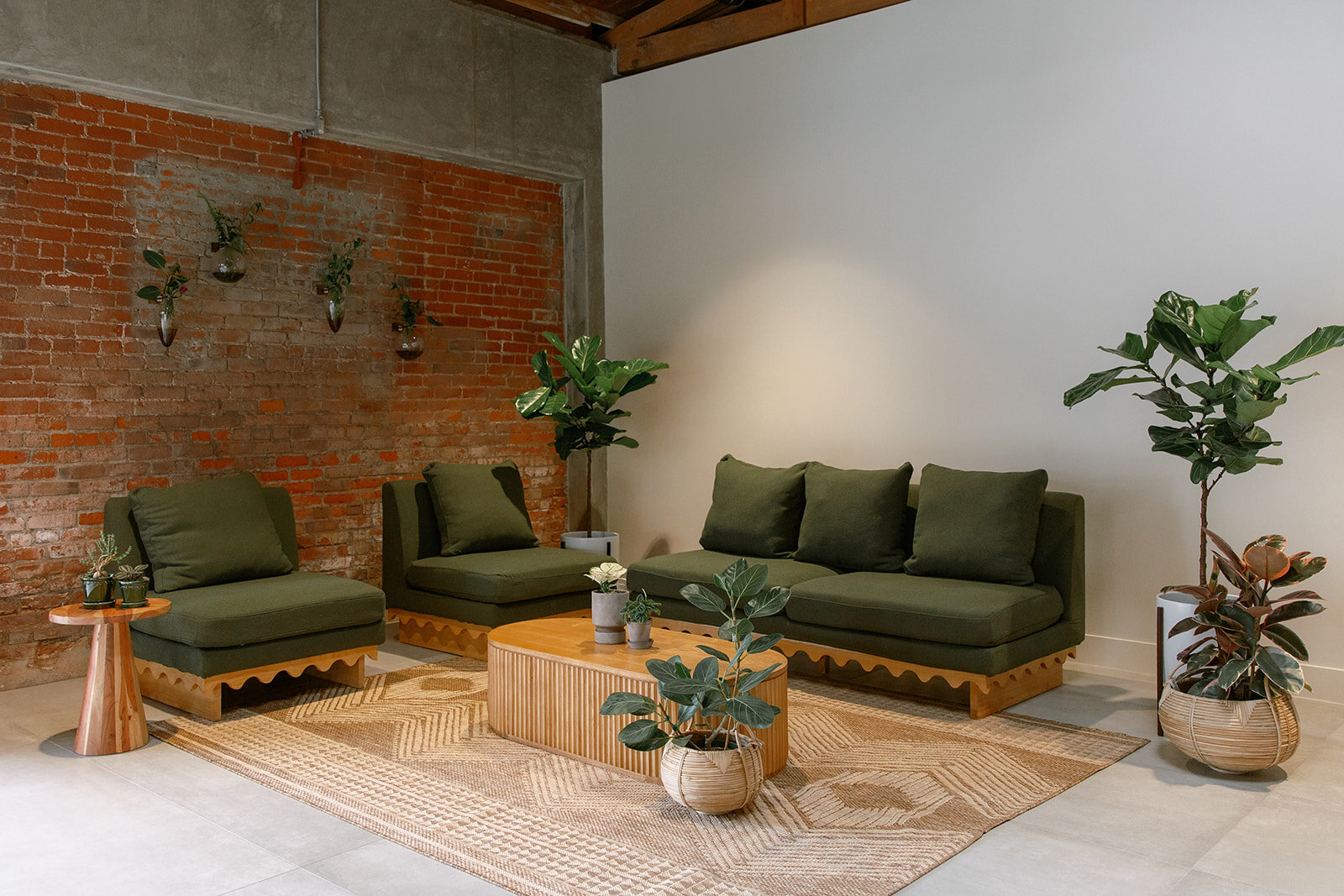 Green cushioned lounge furniture, wood tables and potted plants arranged inside Palomino’s event space.