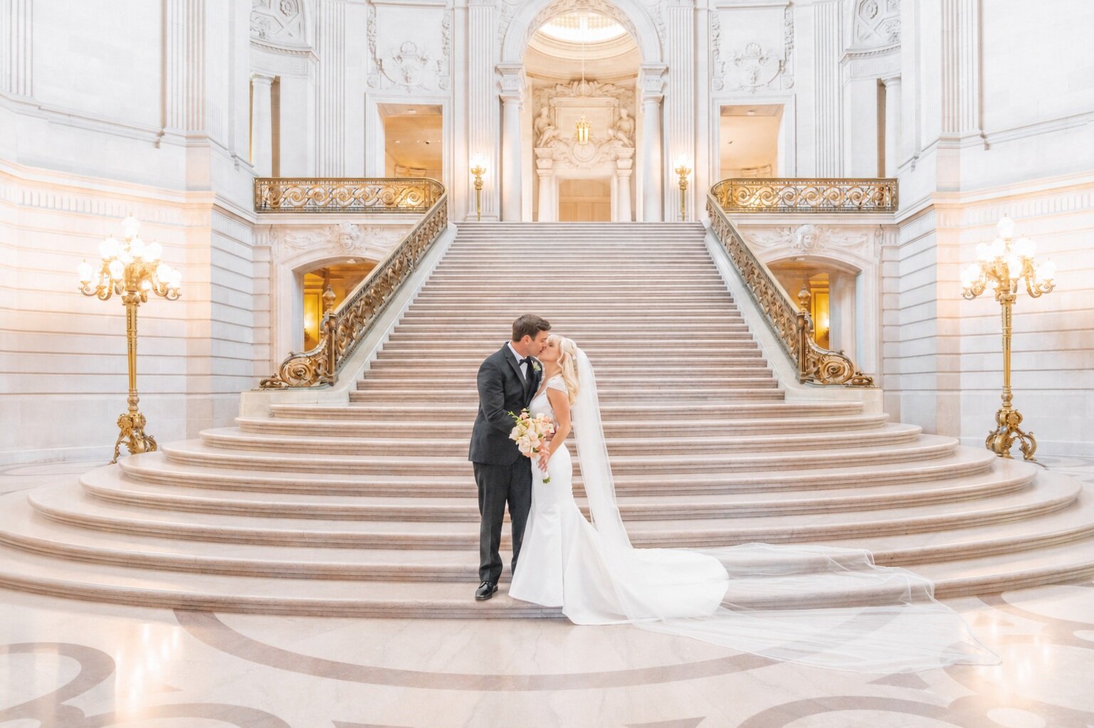 Bride and groom kissing on the grand staircase at San Francisco City Hall