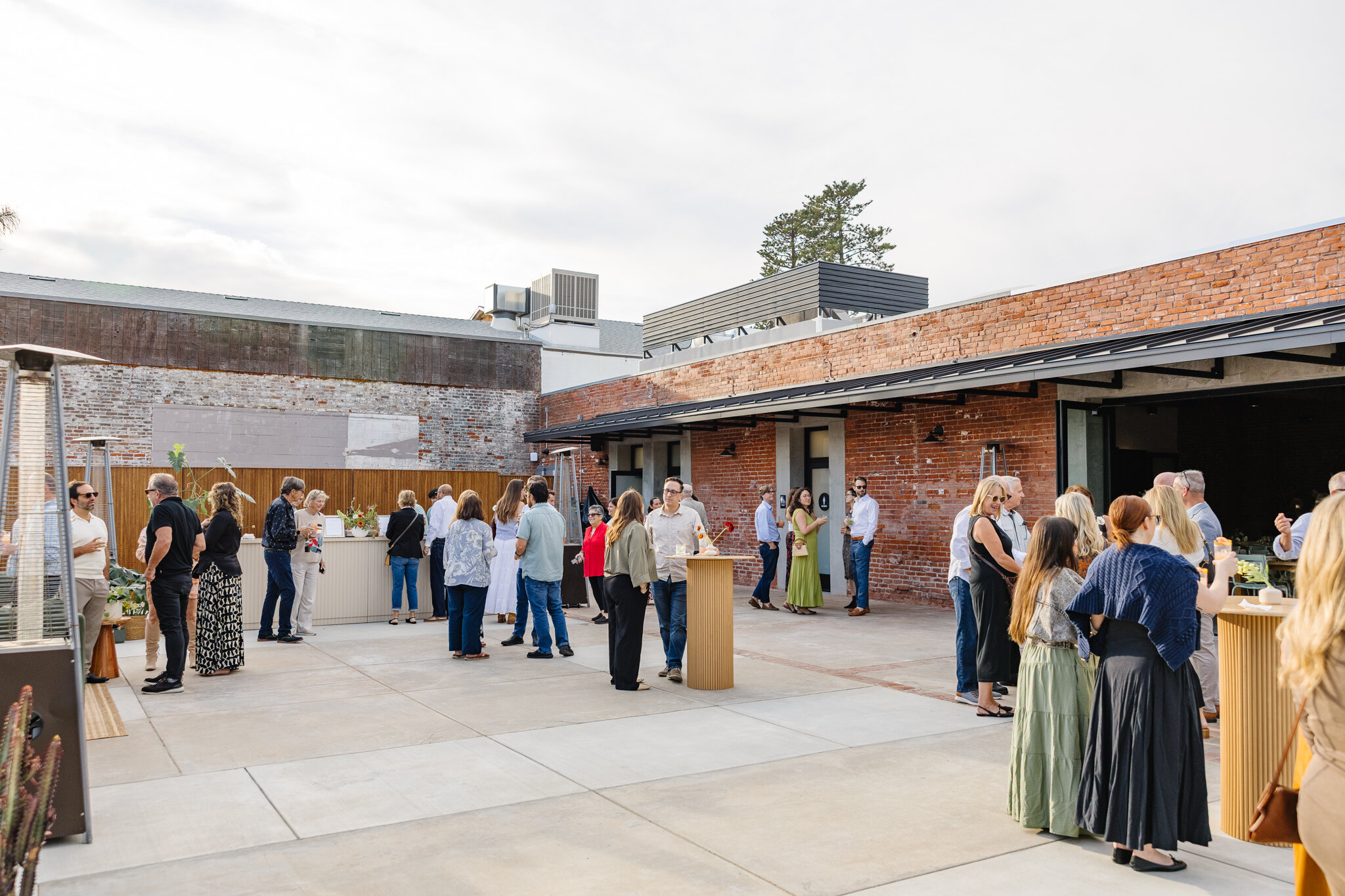 Guests mingling around cocktail tables during an open-air gathering on Palomino’s patio.