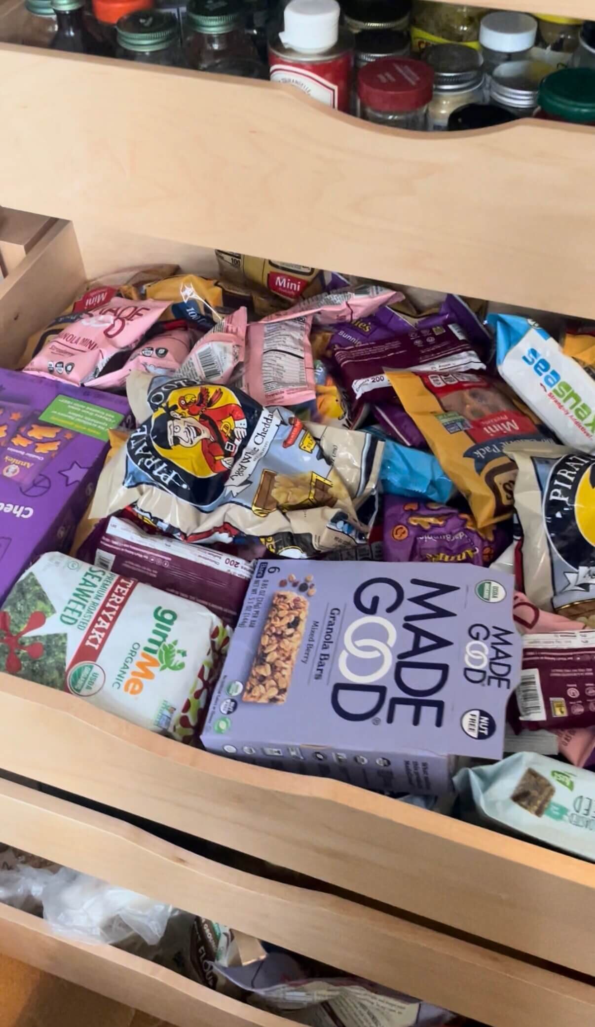 Cluttered kitchen drawer filled with assorted snack bags, granola bars, and packaged food.