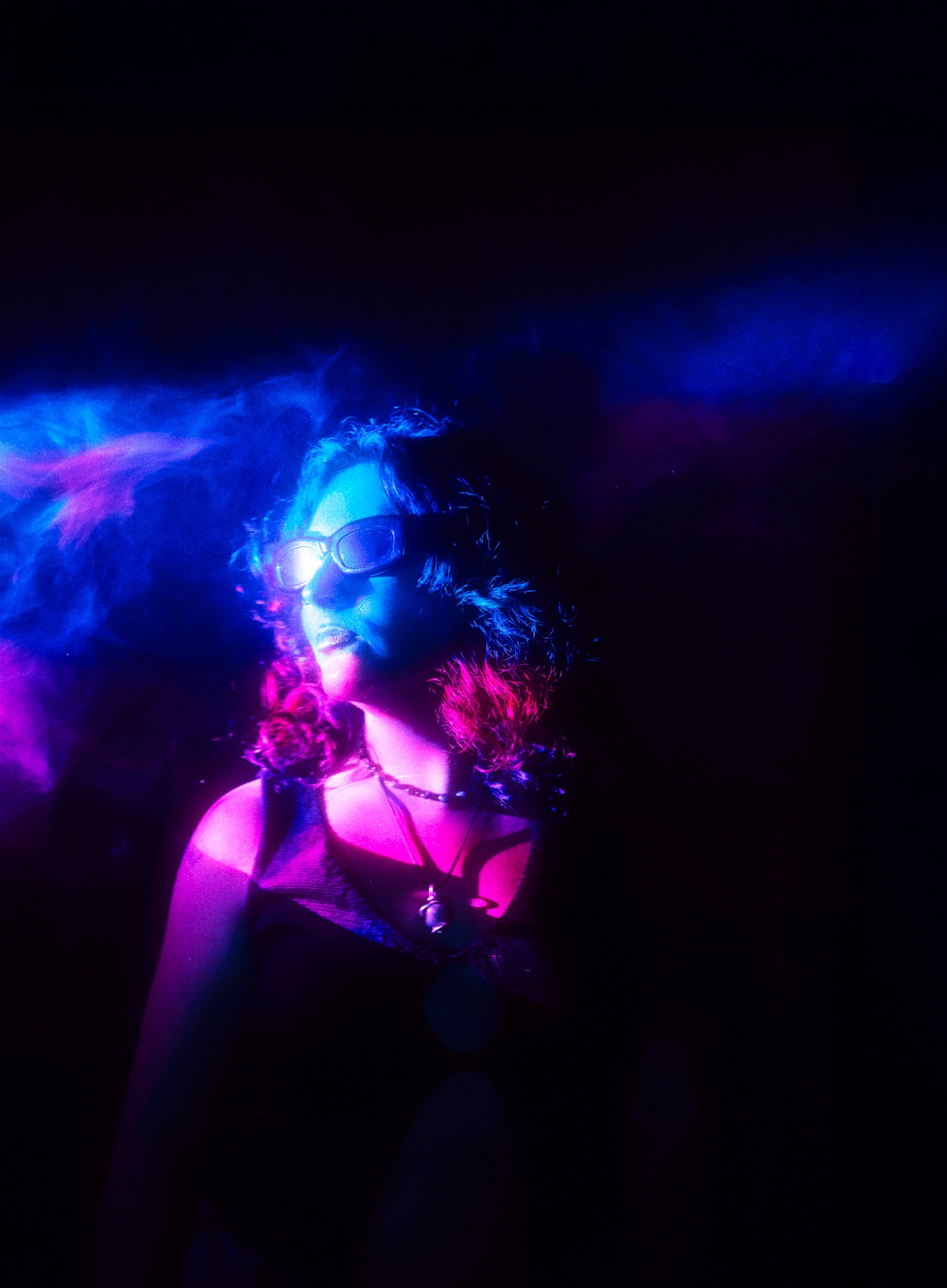 Woman in sunglasses looks away from the camera, shrouded in smoke.