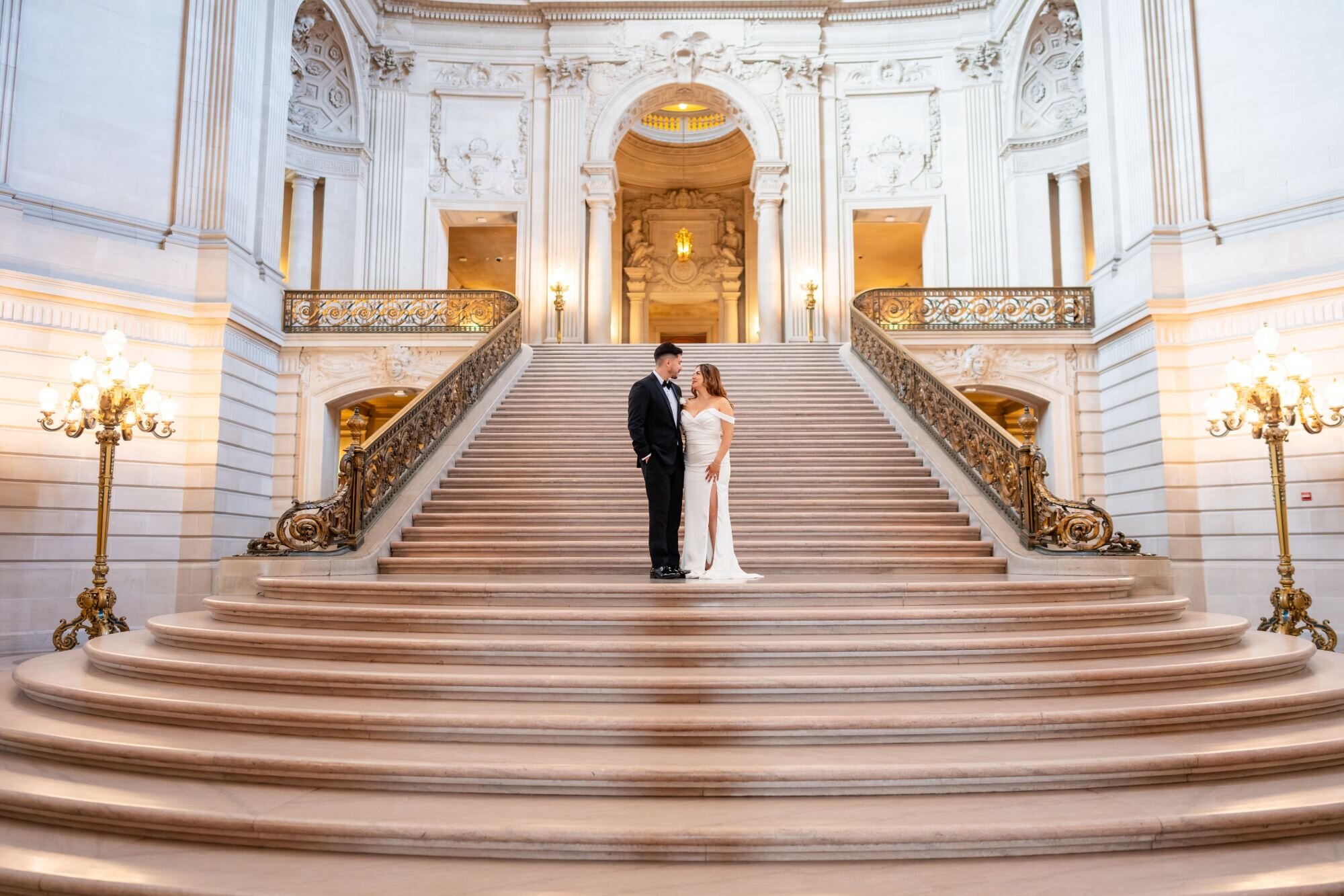 Couple standing at the base of the grand staircase at San Francisco City Hall