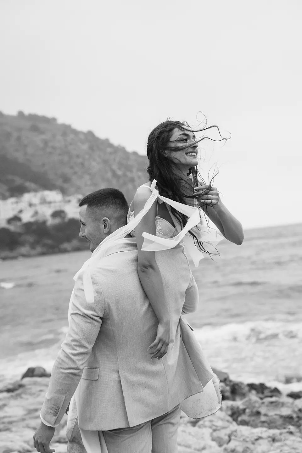 Braut und Bräutigam am Strand von Sylt, Hand in Hand zwischen Dünen und Meer; Spitzenkleid und Bouquet – natürliche Hochzeitsfotografie und Hochzeitsfotograf für eine Hochzeit auf Sylt.