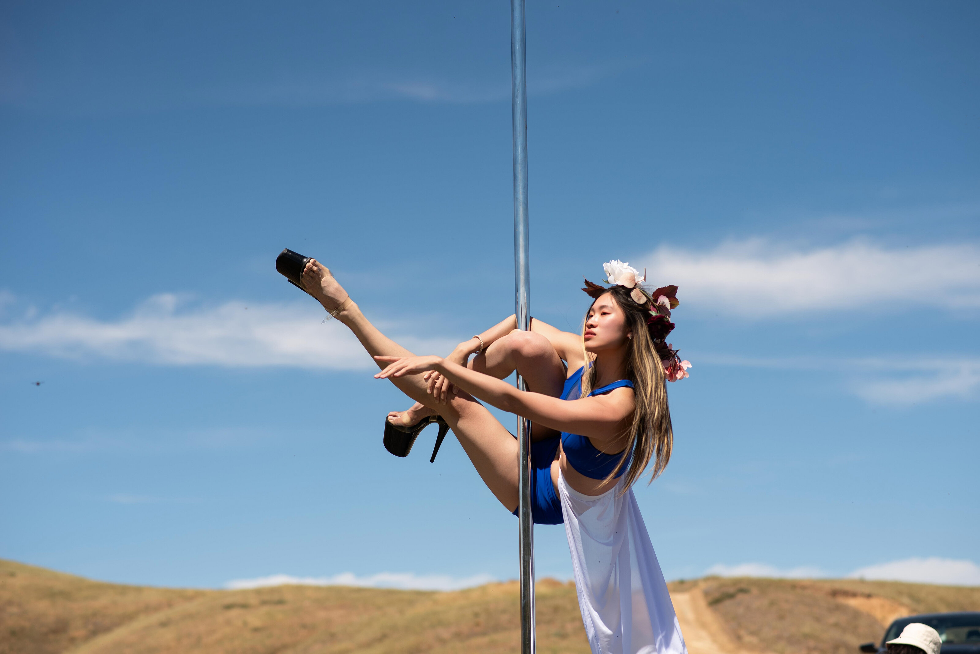 Pole dancer performing outdoors beneath an open blue sky
