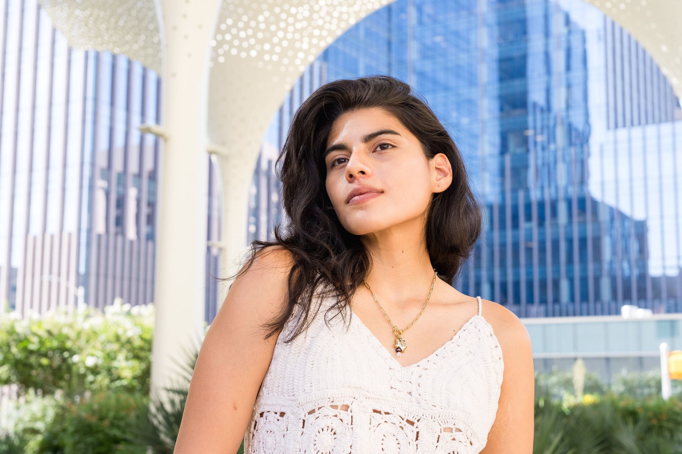 Charm Theory model wearing layered charm necklace with downtown Austin skyline in the background