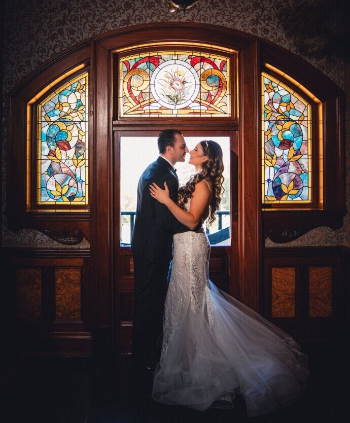 Newlyweds posing beneath a colorful stained-glass doorway