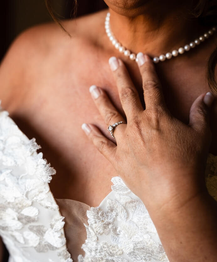 Bride wearing a pearl necklace and engagement ring detail