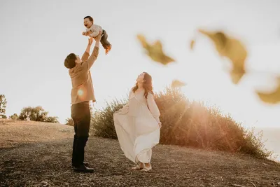 Father tossing his toddler in the air on a golden hillside in the South Bay, Los Angeles