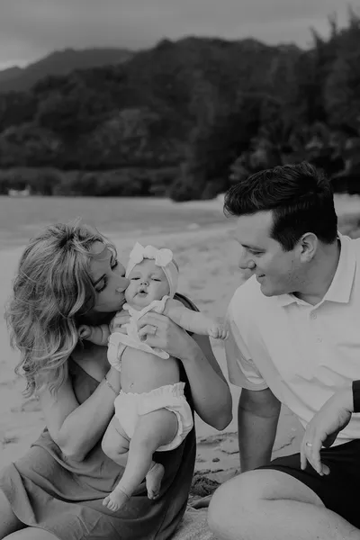 Father holding and kissing his newborn baby's cheek, black and white portrait