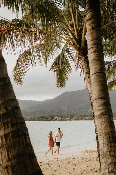 Couple silhouetted beneath palm trees at sunset