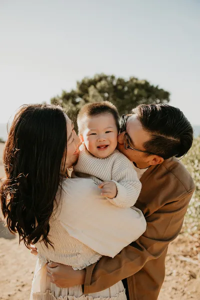 Mother lifting and kissing her newborn baby in soft natural light