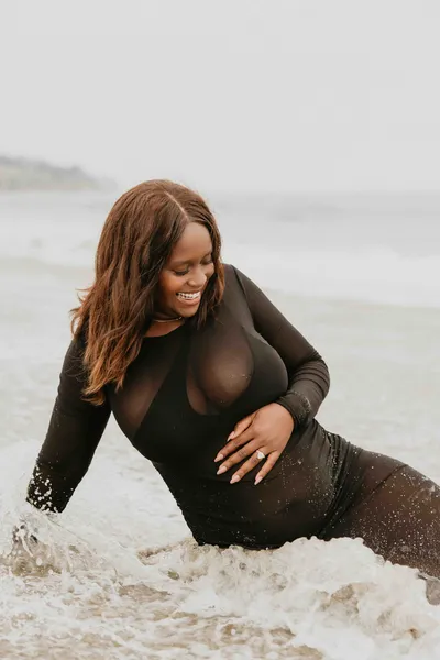 Maternity portrait in a sheer black gown on the beach at sunset in Los Angeles by Indi Families