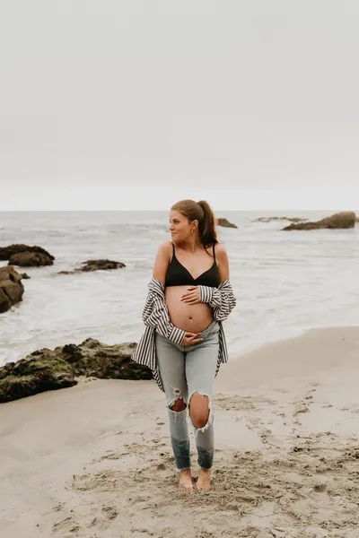 Close up of a bare pregnant belly on the beach at golden hour