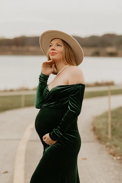 Pregnant woman in a green velvet dress and hat, editorial maternity portrait by Indi Families
