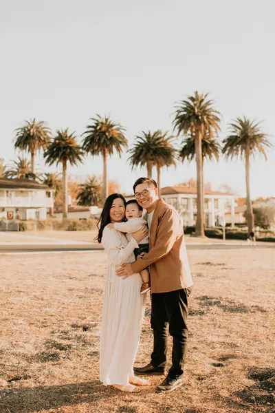Family of three standing beneath palm trees during a family photography session in Los Angeles