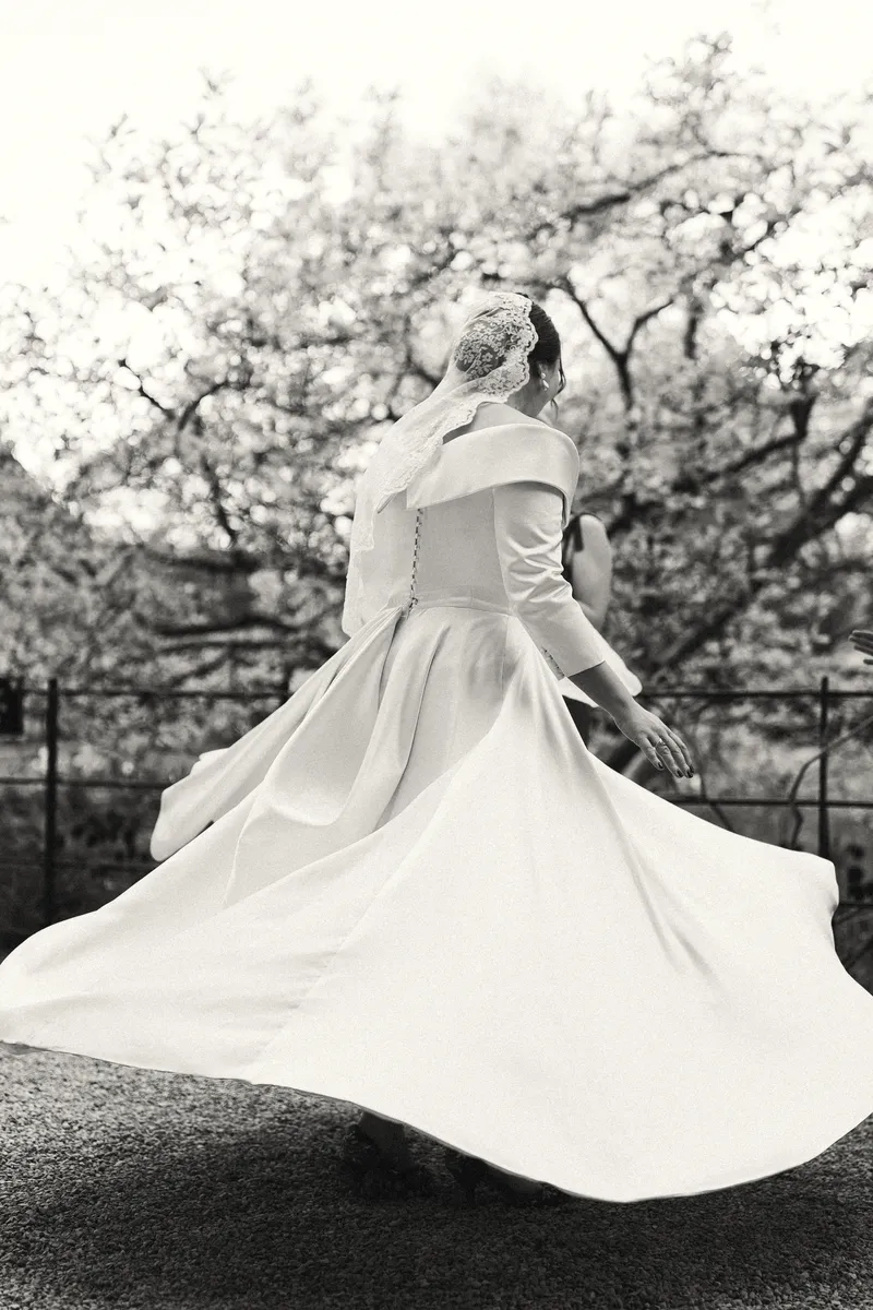 Bride spinning in her wedding dress beneath blossom, shot on 35mm film