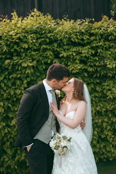 Couple kissing in front of an ivy wall